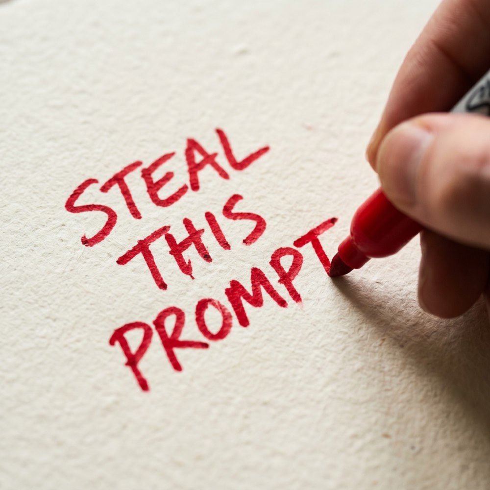 Red marker writing STEAL THIS PROMPT on cream paper